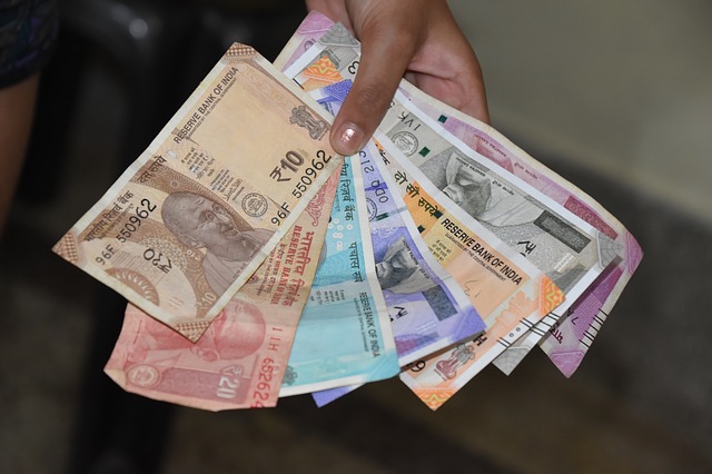 ruka plná indických bankovek